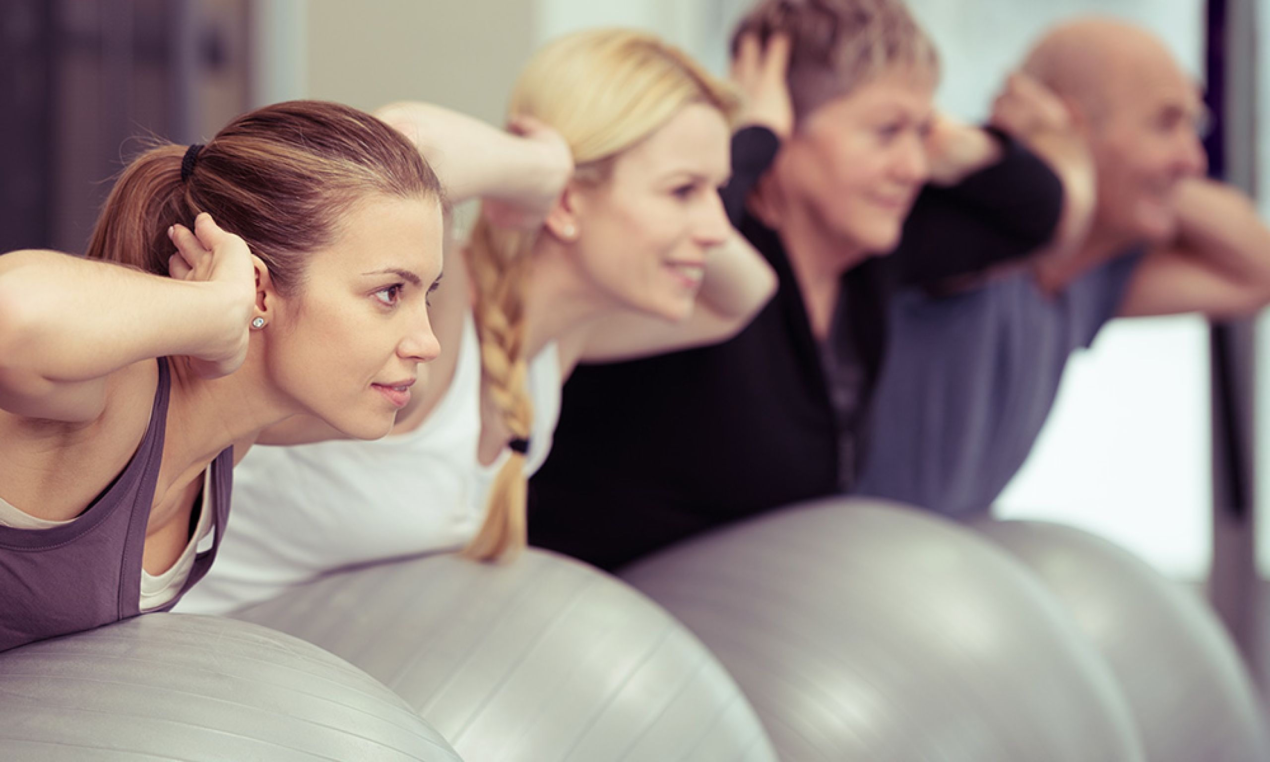 gemischte Gruppe auf Gymnastikbällen im Rückentraining